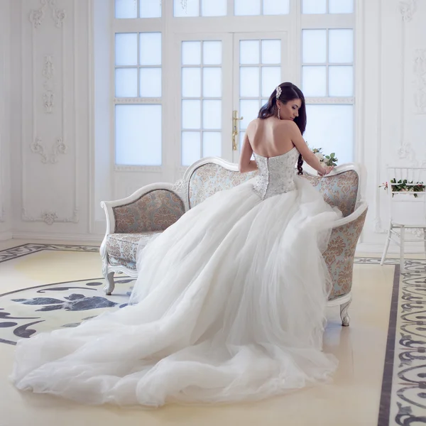 Porträt der schönen lachenden Braut. Hochzeitskleid mit offenem Rücken. luxuriöses helles Interieur — Stockfoto