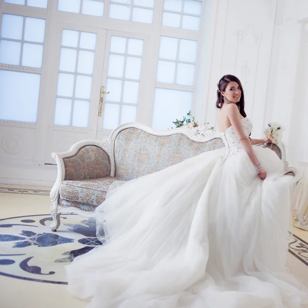 Retrato de una hermosa novia riendo. Vestido de novia con espalda abierta. Lujoso interior de luz — Foto de Stock