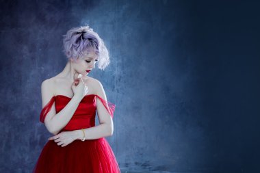 Kırmızı elbiseli genç muhteşem kadın moda fotoğrafı. Dokulu arka plan