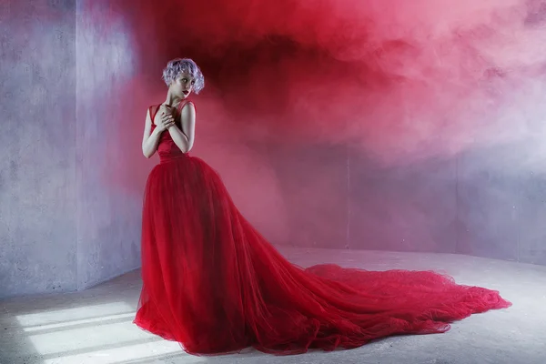 Photo de mode de jeune femme magnifique en robe rouge. Fond texturé, fumée — Photo