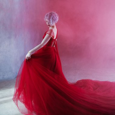 Kırmızı elbiseli genç muhteşem kadın moda fotoğrafı. Dokulu arka plan, duman
