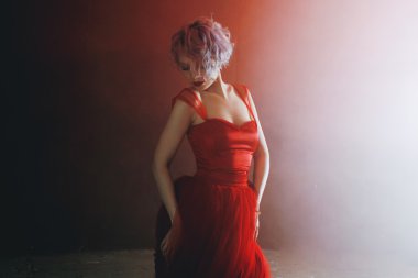 Kırmızı elbiseli genç muhteşem kadın moda fotoğrafı. Dokulu arka plan, mor duman