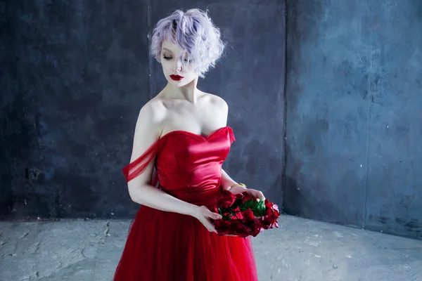 Young magnificent woman in red dress holds a wreath of roses. Textured background — Stock Photo, Image