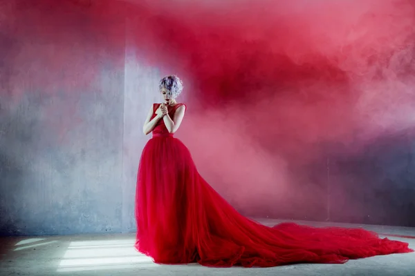 Foto de moda de la joven mujer magnífica en vestido rojo. Fondo texturizado, humo —  Fotos de Stock