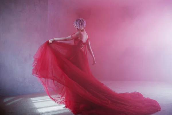 Foto de moda de la joven mujer magnífica en vestido rojo. Fondo texturizado, humo — Foto de Stock