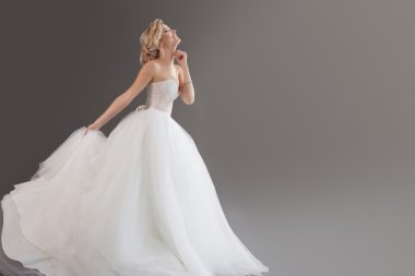 Lüks gelinlik büyüleyici genç gelin. Güzel kız beyaz. Metni sağ duygu mutluluk, kahkaha ve gülümseme, gri arka plan, yer