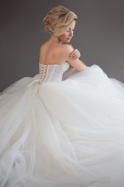 Lüks gelinlik büyüleyici genç gelin. Güzel kız beyaz. Gri arka plan. Geri