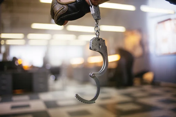 Criminal man. Hand male in unbuttoned handcuffs, on background of the police station — Stock Photo, Image