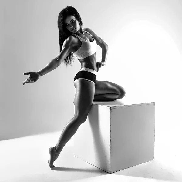 Cuerpo musculoso femenino. Joven atleta fuerte posando en cubo. Foto en blanco y negro en contraste —  Fotos de Stock