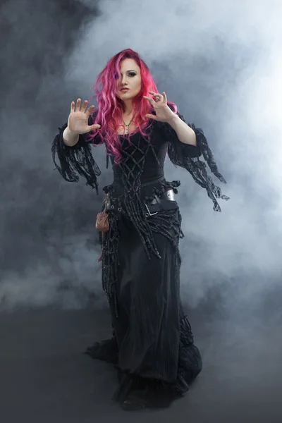 A bruxa cria magia. Mulher atraente com cabelo vermelho no traje de bruxas — Fotografia de Stock