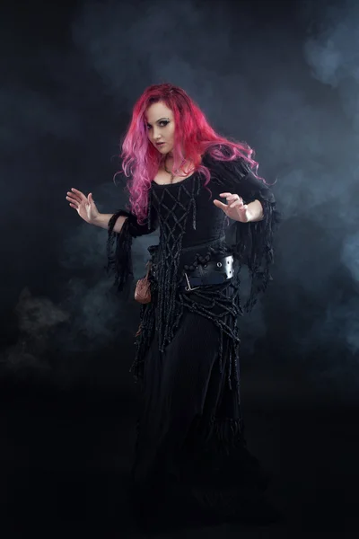 Witch creates magic. Attractive woman with red hair in witches costume — Stock Photo, Image