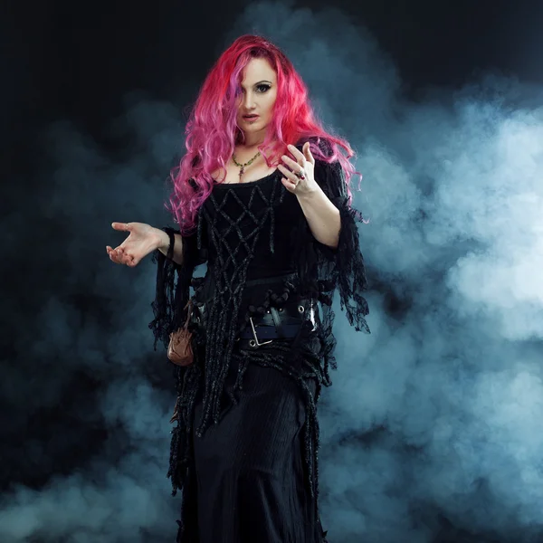 La bruja crea magia. Mujer atractiva con el pelo rojo en traje de brujas —  Fotos de Stock
