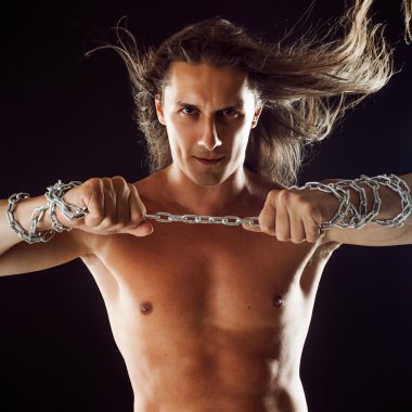 Uzun saçlı genç adam Demir zinciri keser. Güçlü. Direnç kavramı