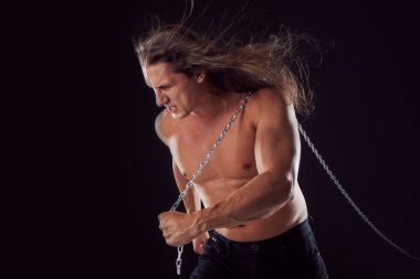 Arkasında bir şey sürükleyerek uzun saçlı genç adam. Güçlü.