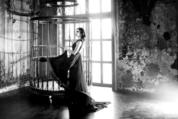 Skönhet Brunett modell kvinna i aftonklänning nära en gigantisk bur — Stockfoto
