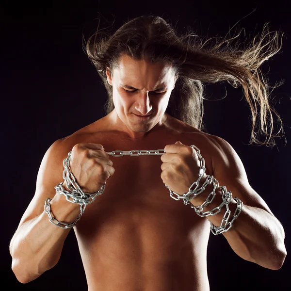 Young man with long hair breaks the iron chain. Strong. Concept of resistance — Stock Photo, Image