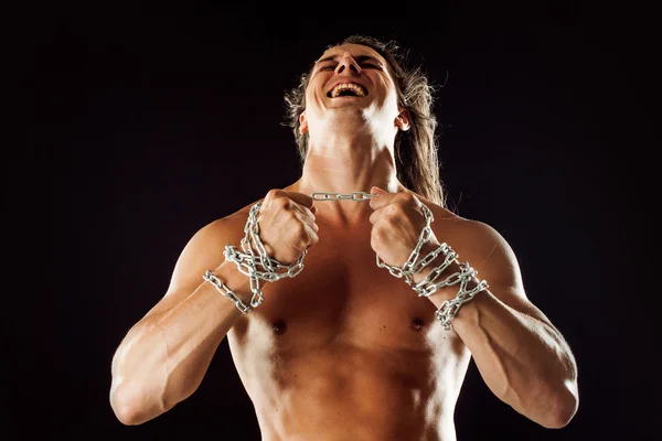 Jonge man met lange haren breekt de ijzeren ketting. Strong. Concept van weerstand — Stockfoto