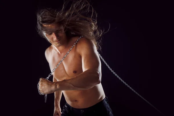 Young man with long hair dragging something behind him. Strong. — Stock Photo, Image