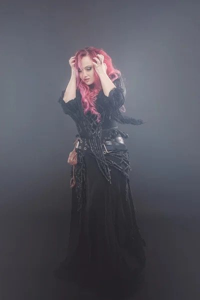 Mujer atractiva con el pelo rojo en traje de brujas, en la niebla, agarrando su cabeza —  Fotos de Stock
