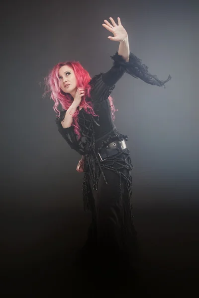 Belle femme aux cheveux roux en costume de sorcière, dans le brouillard, serrant la tête — Photo