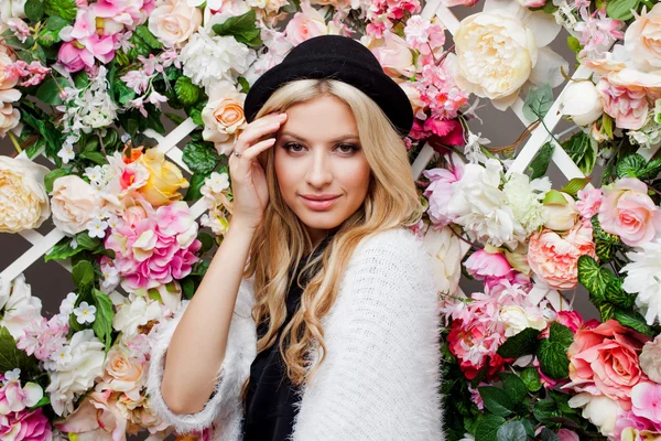 Jonge mooie blonde vrouw in trendy hoed op florale achtergrond — Stockfoto