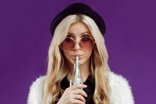 Jeune belle femme blonde au chapeau à la mode. Boire du soda dans des bouteilles en verre. Très surpris — Photo