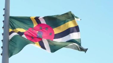 Dominica bayrağı rüzgarda dalgalanıyor. Mavi gökyüzüne karşı ulusal bayrak,