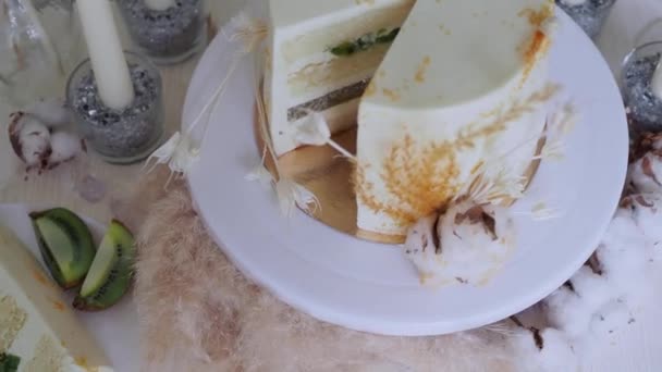 Vacker bröllopstårta med grädde och kiwi, dukning och en bit tårta på en tallrik. — Stockvideo