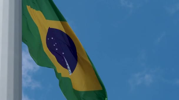 Braziliaanse vlag wapperend in de wind. Nationale vlag tegen een blauwe lucht, — Stockvideo