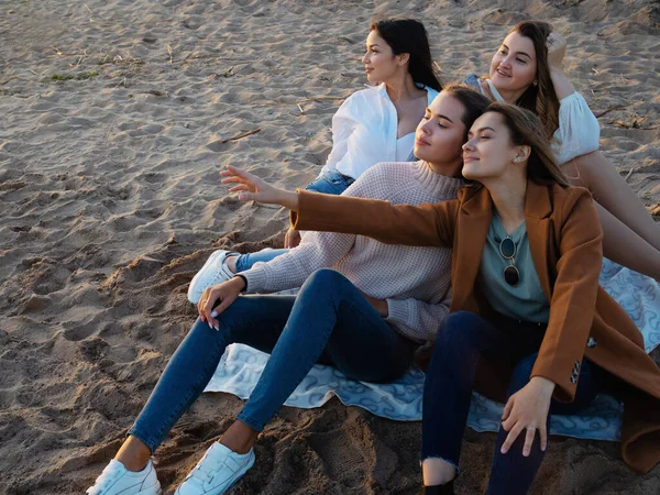 Grupo de mujeres jóvenes en un picnic en la playa, disfrutando de la puesta de sol. Reunión con amigos, — Foto de Stock