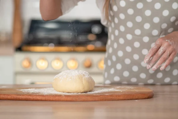 Knead dough, hand dough and flour close-up. A pastry chef in a grey polka-dot apron.