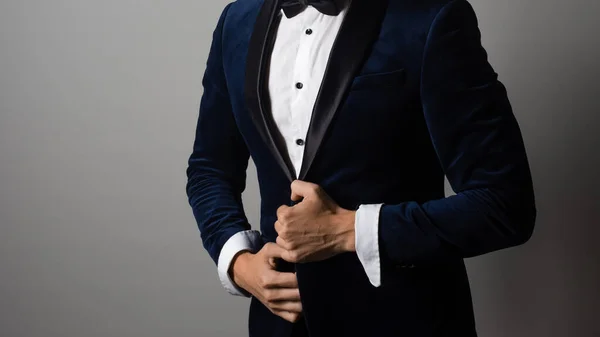 Man in a tuxedo with a bow tie buttoning his jacket or adjusting his sleeve, — Stock Photo, Image