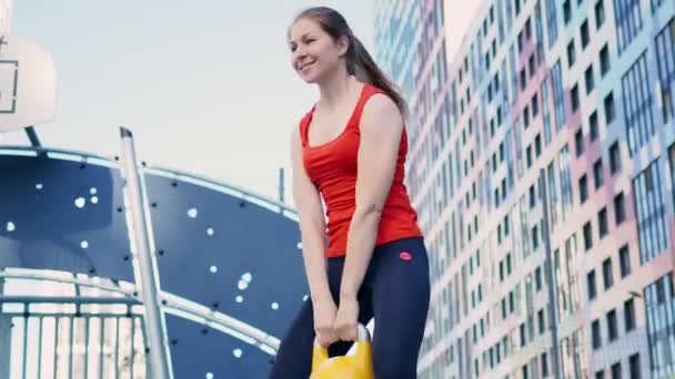 Молодая спортсменка занимается спортом, тренируется с гирями на открытом воздухе. — стоковое видео