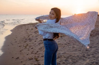 Genç ve güzel bir kadın sıcak bir battaniyeye sarılmış, kumsalda sıcak ve samimi..