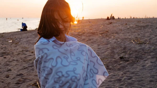 Junge schöne Frau eingewickelt in eine warme Decke, warm und gemütlich am Strand. — Stockfoto
