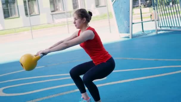 Jeune athlète féminine faisant de l'entraînement, s'entraînant avec une kettlebell en plein air. — Video