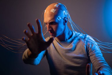 Kabloları olan kel kafalı bir adam. Korku ve endişe. Beynin incelenmesi,