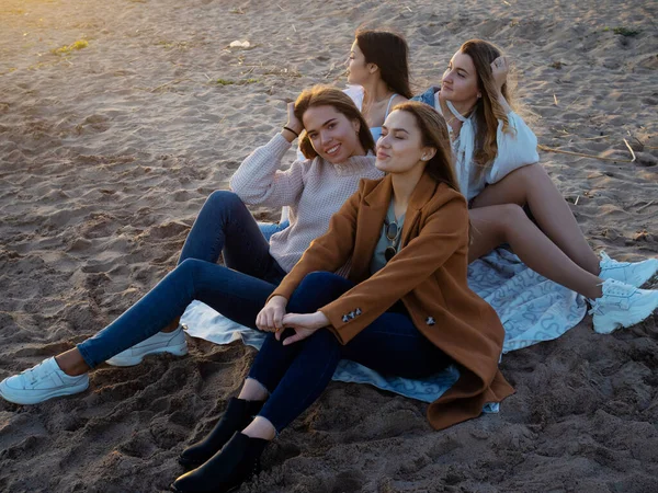 Grupo de mujeres jóvenes en traje casual en la playa, disfrutando de la puesta de sol. — Foto de Stock