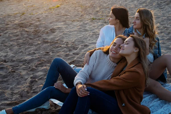 Grupo de mujeres jóvenes en un picnic en la playa, disfrutando de la puesta de sol. Reunión con amigos, — Foto de Stock