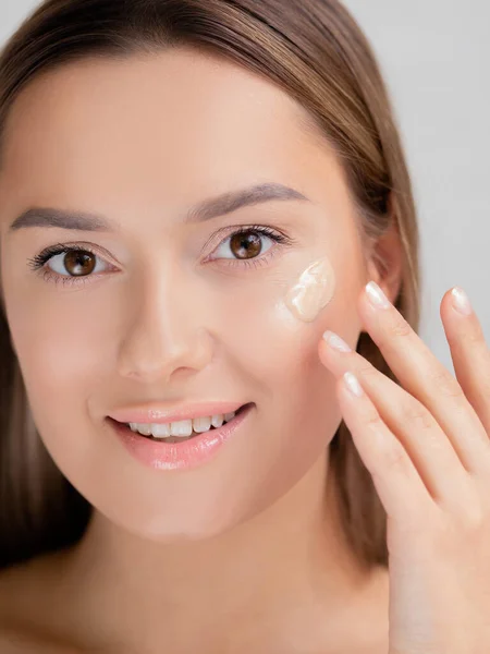 Cuidado facial y maquillaje, una mujer joven aplica Fundación a la piel. — Foto de Stock