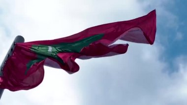 Maldivler rüzgarda dalgalanıyor. Mavi gökyüzüne karşı ulusal bayrak,