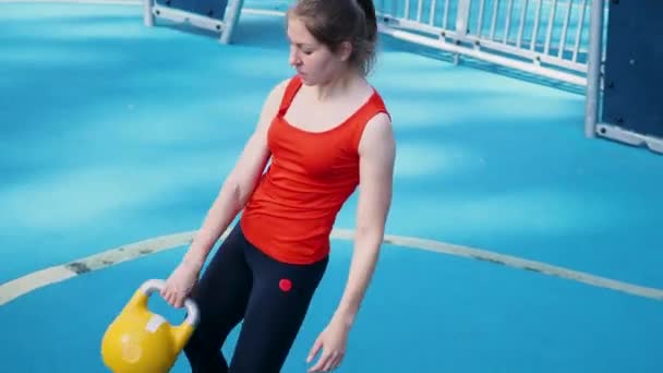 Jonge vrouwelijke atleet doen workout, training met een kettlebell in de open lucht. — Stockvideo