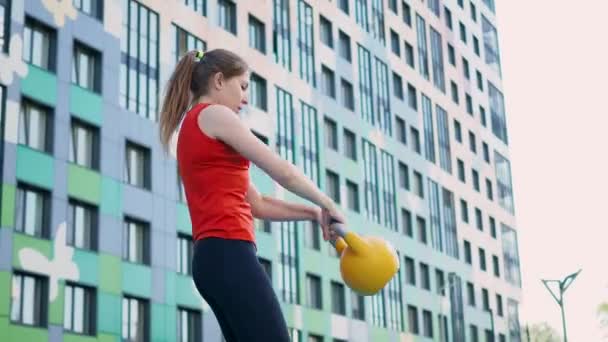 若い女性アスリートは、屋外でケトルベルでトレーニングを行います. — ストック動画