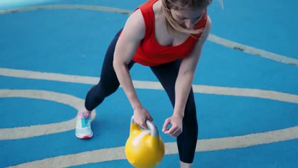 Ung kvinnlig idrottare gör träning, utbildning med en kettlebell i det fria. — Stockvideo