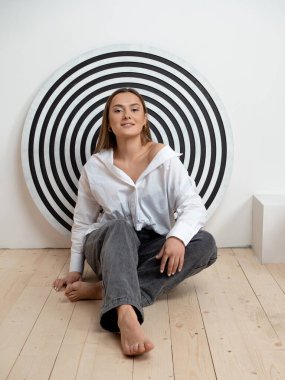 Genç hırslı esmer, konsept. Yerde oturan genç bir kadın eşmerkezli çemberlerin arka planında,