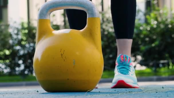Aan de slag. Jonge vrouwelijke atleet doen workout, training met een kettlebell in de open lucht. — Stockvideo