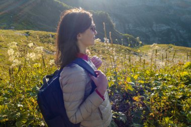 Doğadaki mutlu genç kadın Dağlarda, güneş ışığı ve parıltı.