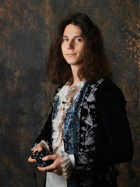 Digitale Renaissance, Konzept. Der Typ ist ein Spieler im mittelalterlichen Kostüm mit einem Gamepad in der Hand. — Stockfoto