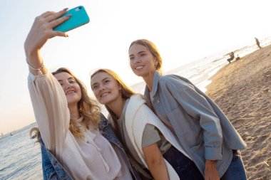 Kumsalda yürüyen üç arkadaş, iletişimin mutluluğu..