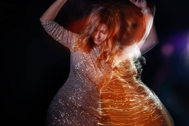 Gece kulübünde dans eden parlak elbiseli güzel bir kadın.,